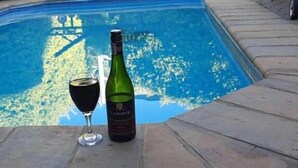 A pool with a bottle and glass of wine on the edge. - Uzuri Guesthouse (Windhoek)