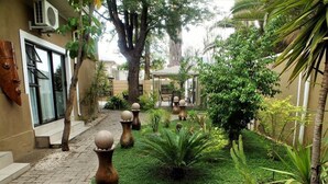 A courtyard with a paved walkway, surrounded by lush greenery and decorative vases. - Uzuri Guesthouse (Windhoek)