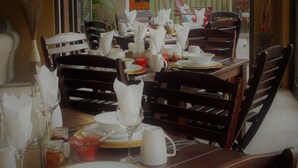A dining area with wooden chairs and tables set for a meal. - Uzuri Guesthouse (Windhoek)