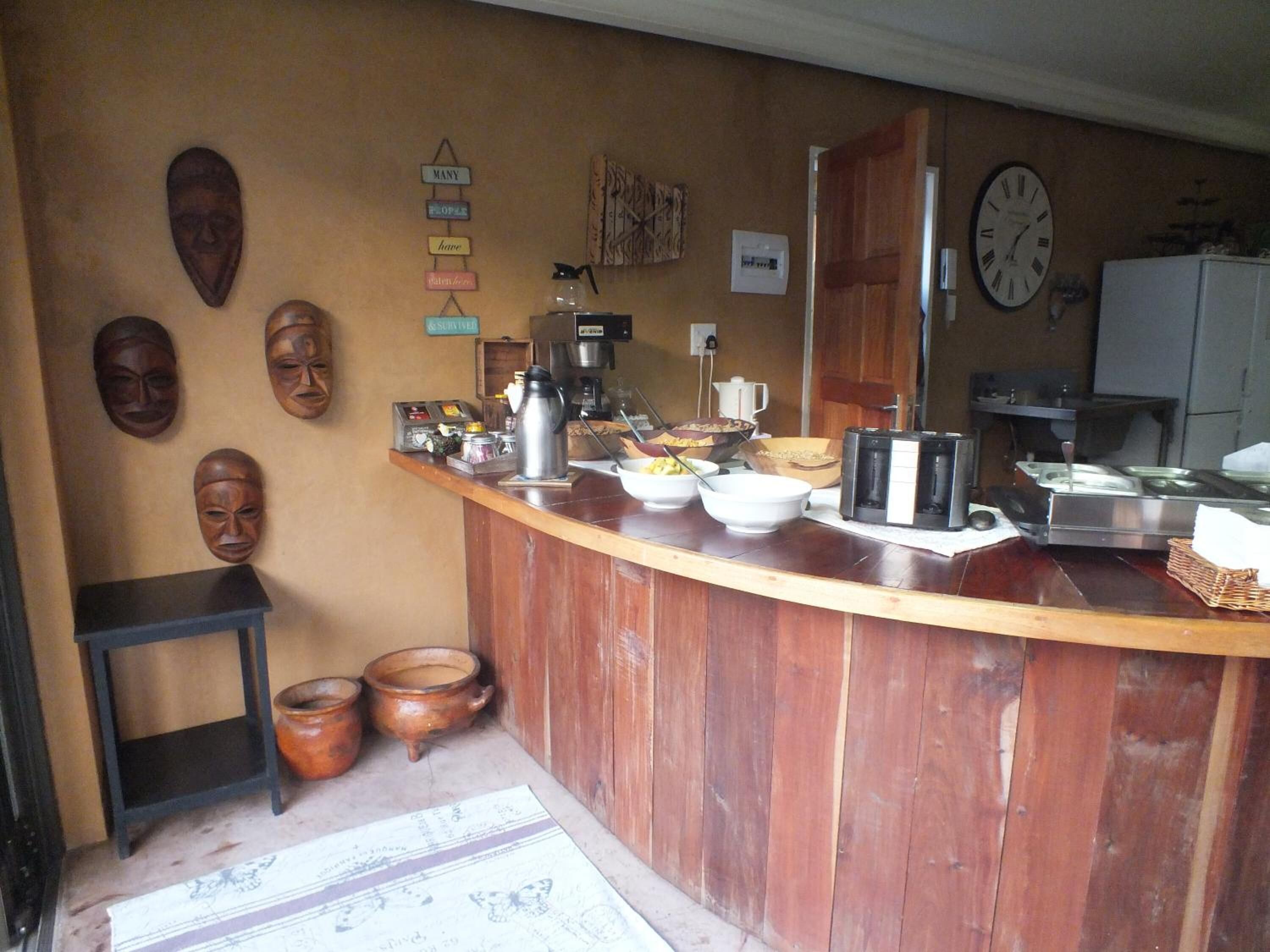 Una cocina con mostrador de madera, cafetera y diversos utensilios de cocina. Hay cuencos de madera y una jarra de café sobre el mostrador.