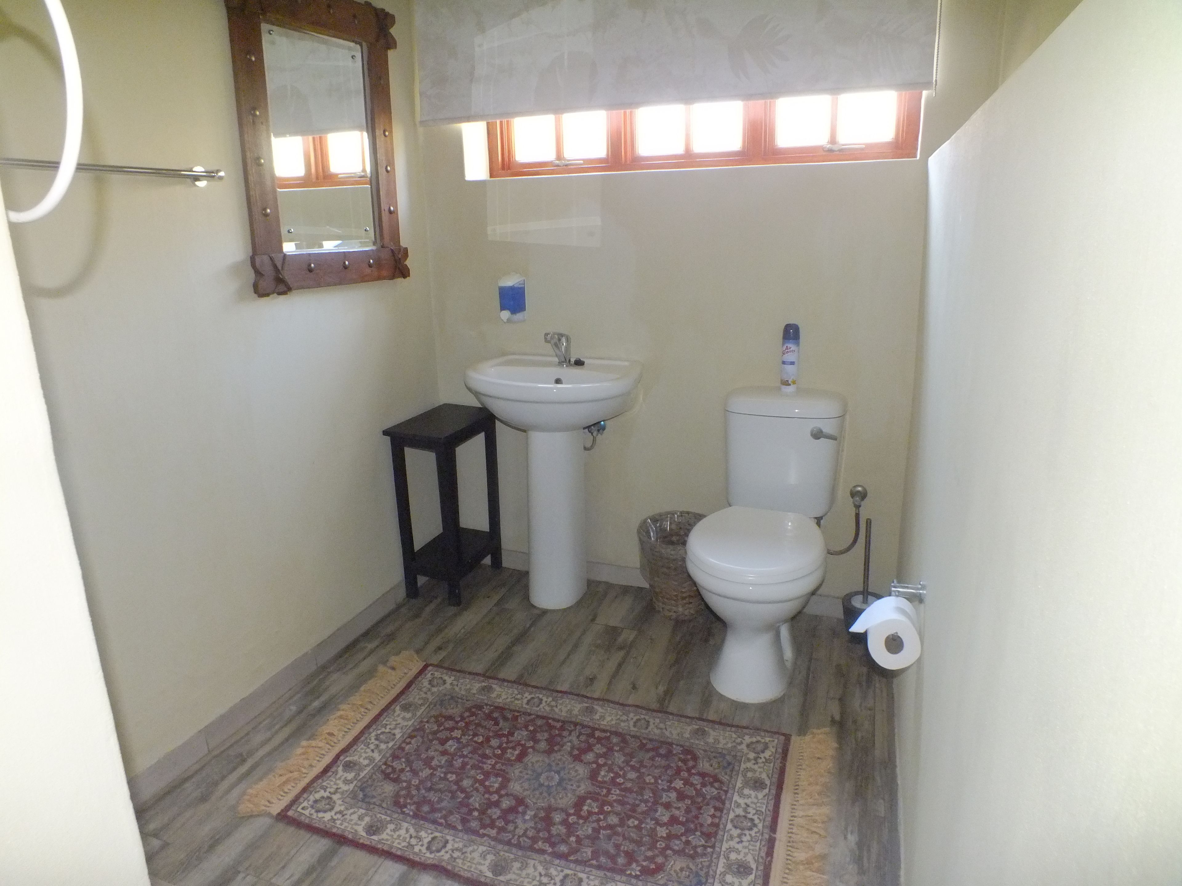 Casa de banho com lavatório, sanita e um pequeno banquinho de madeira.