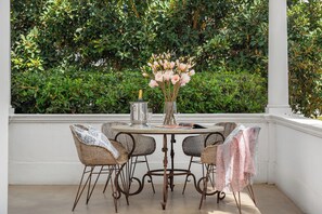 A round table with wicker chairs, a vase with flowers, and a bottle of champagne. - Linda Vista (Cape Town)