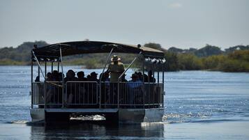 A boat with a covered deck and metal railings, carrying passengers on a body of water.