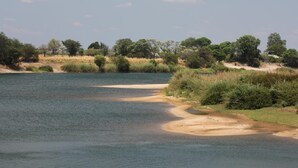 A river with sandy banks and dense vegetation. - Zambezi Mubala Camp (Katima Mulilo)