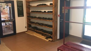 A room with a shoe rack against the wall, a door with a sign, and a window. - Refuge des étangs de Bassiès - Hostel (Auzat)