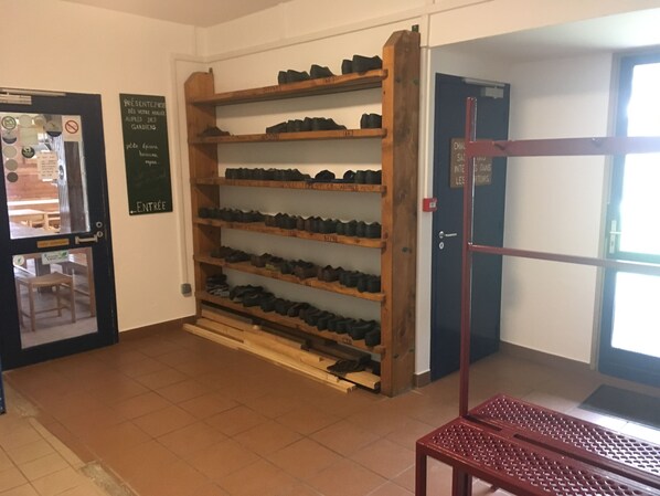 Una habitación con un zapatero junto a la pared, una puerta con un cartel y una ventana.
