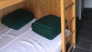 A bunk bed with a wooden frame, white bedding, and green folded blankets. - Refuge des étangs de Bassiès - Hostel (Auzat)