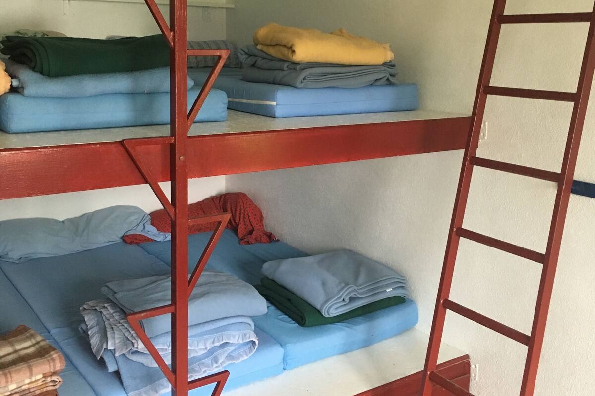 A bunk bed with multiple levels, each with a mattress and pillows. A ladder is attached to the side of the bed.