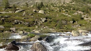 A mountainous landscape with a flowing river in the foreground, rocky terrain, and sparse vegetation. - Refuge des étangs de Bassiès - Hostel (Auzat)