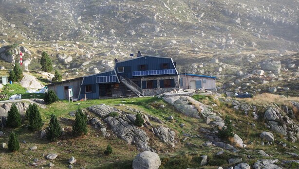 A modern building with a blue roof, situated on a rocky hillside with a view of the surrounding landscape. - Refuge des étangs de Bassiès - Hostel (Auzat)
