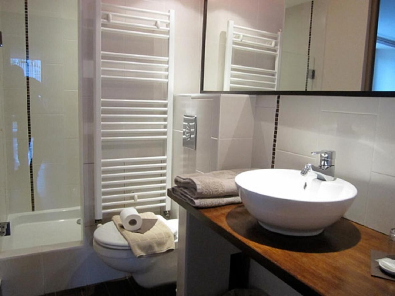 A modern bathroom with a white bathtub, a white sink, and a toilet.