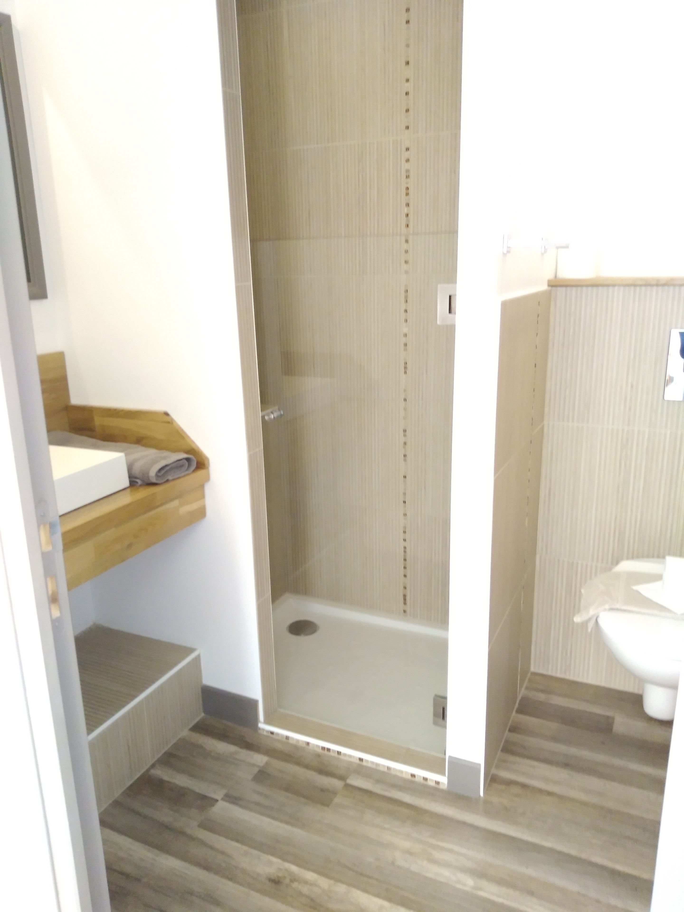 Een moderne badkamer met een douche, een wastafel en een toilet.