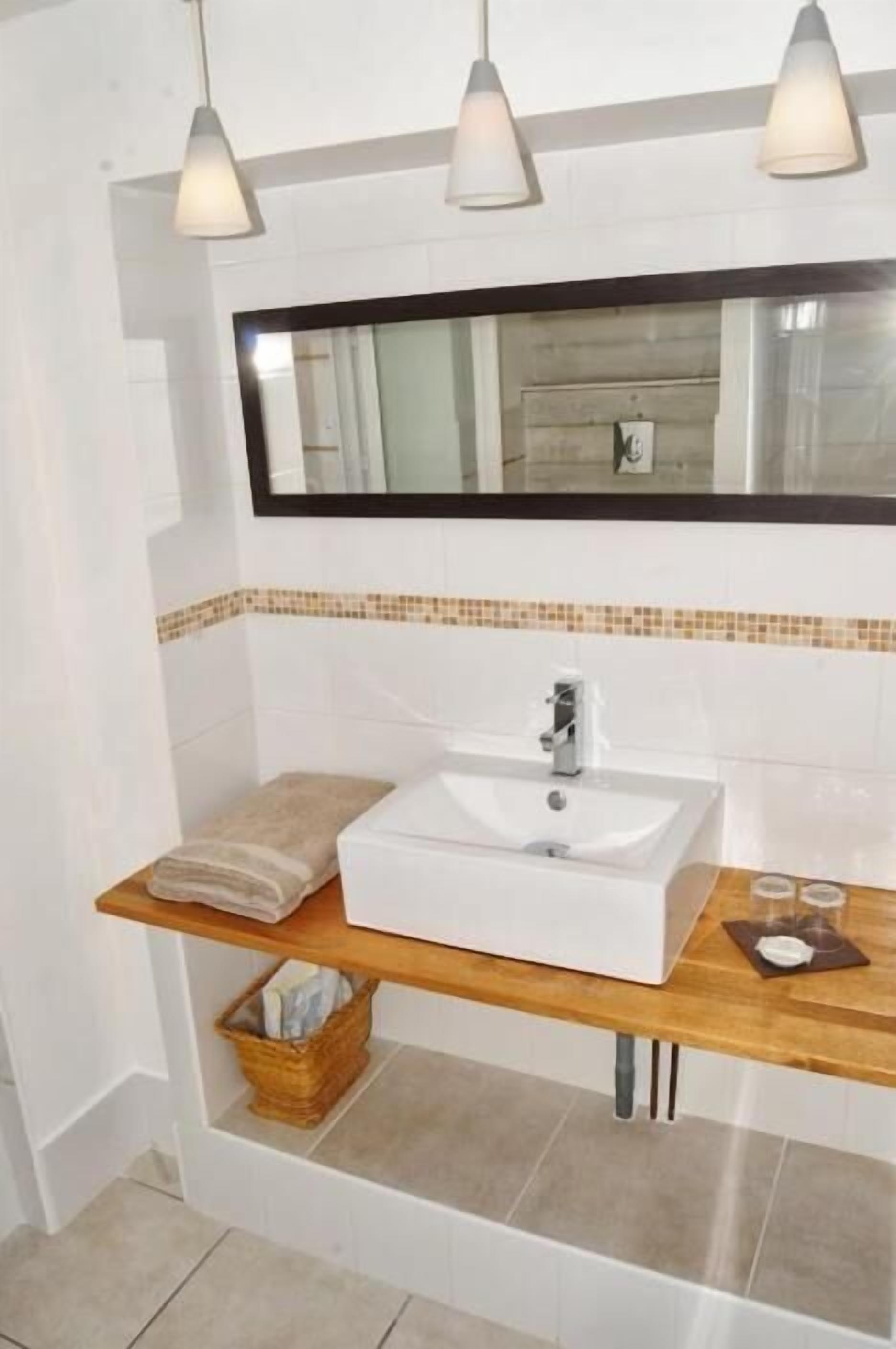 Un baño con un lavabo blanco, un espejo y una toalla sobre una repisa.