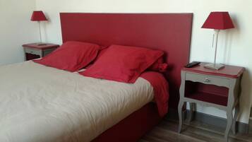 A bed with red bedding, two bedside tables with lamps, and a red headboard.