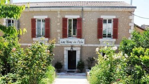Edifici amb un rètol que diu “Les Rives de l'Isle” i un jardí ple de plantes i flors diverses.