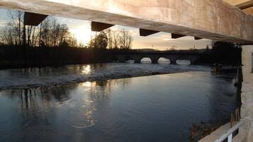 Un río bajo un puente con un muro de piedra a un lado.
