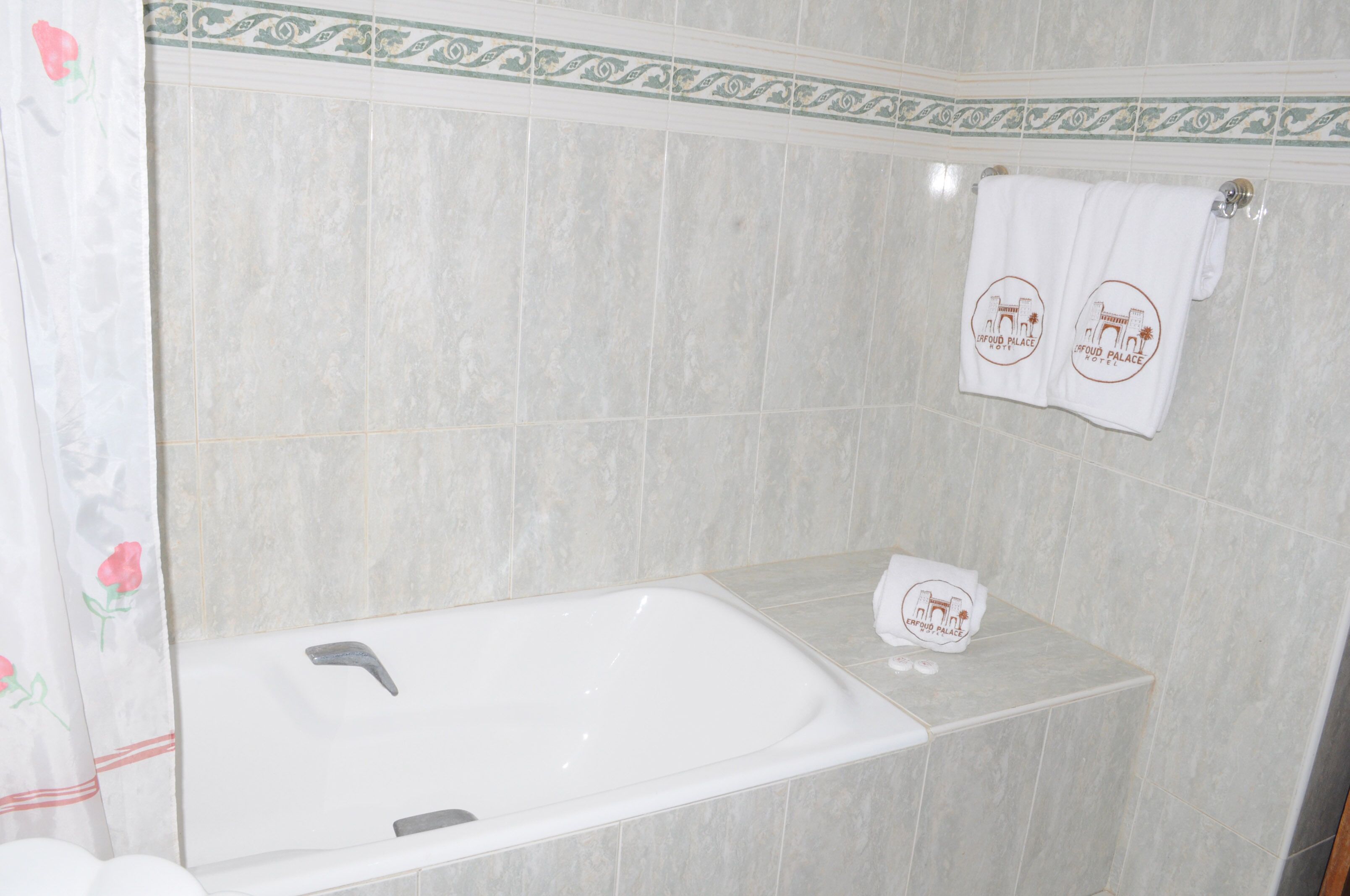 A bathroom with a bathtub, a towel rack with towels, and a decorative border on the wall.