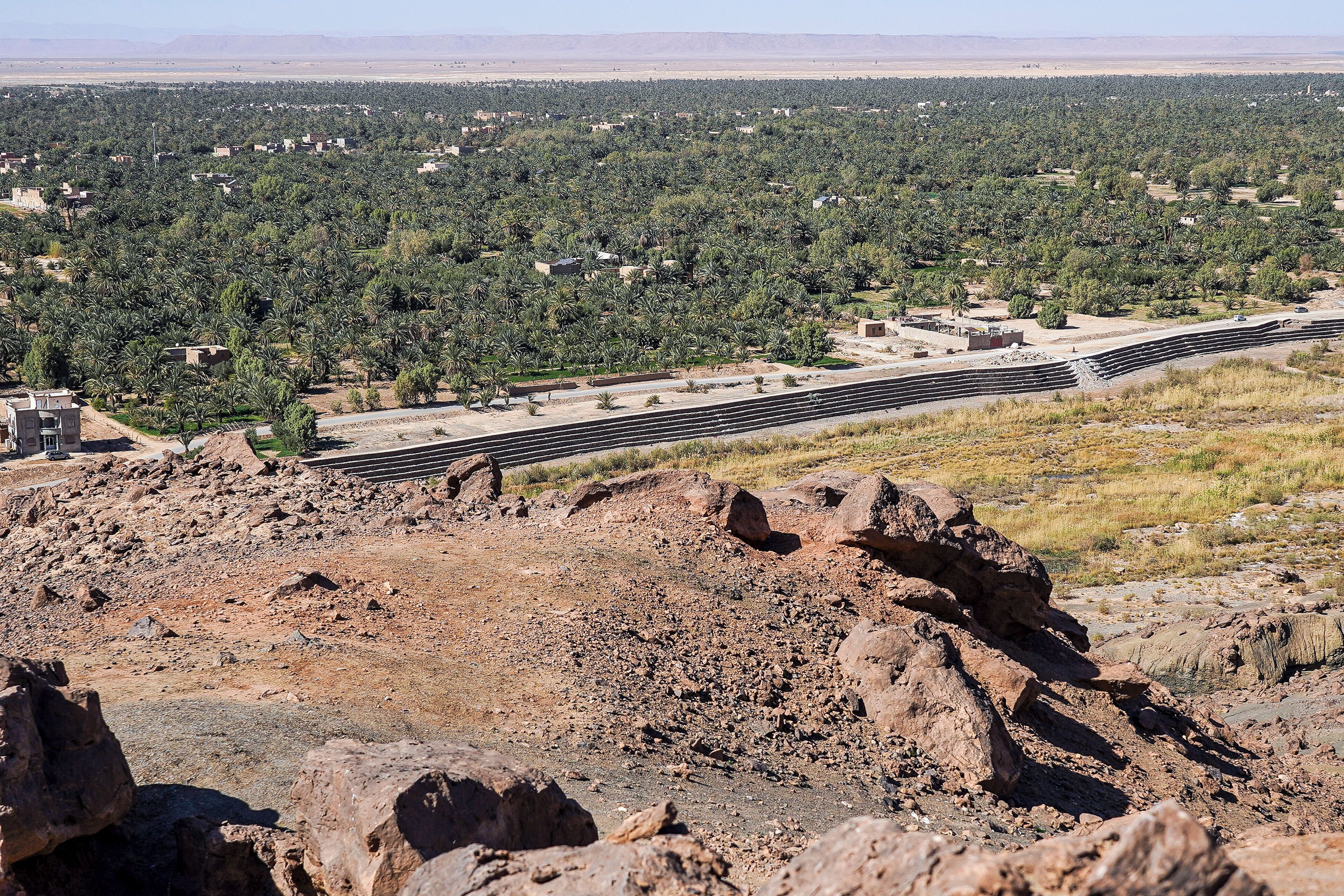 A desert landscape with a road, rocky terrain, and scattered buildings.