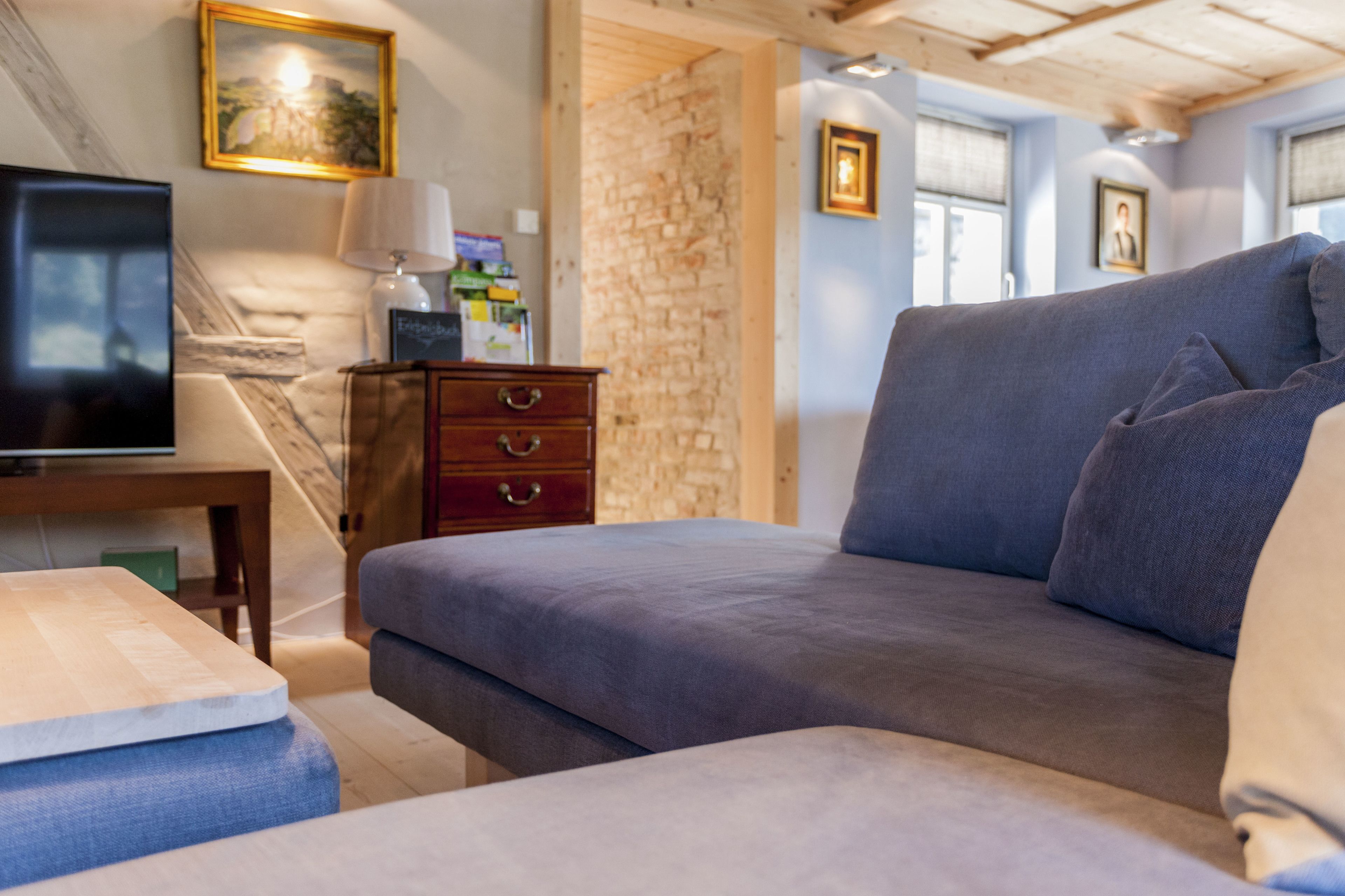 A cozy room with a sofa, a TV, a wooden table, and a stone wall.