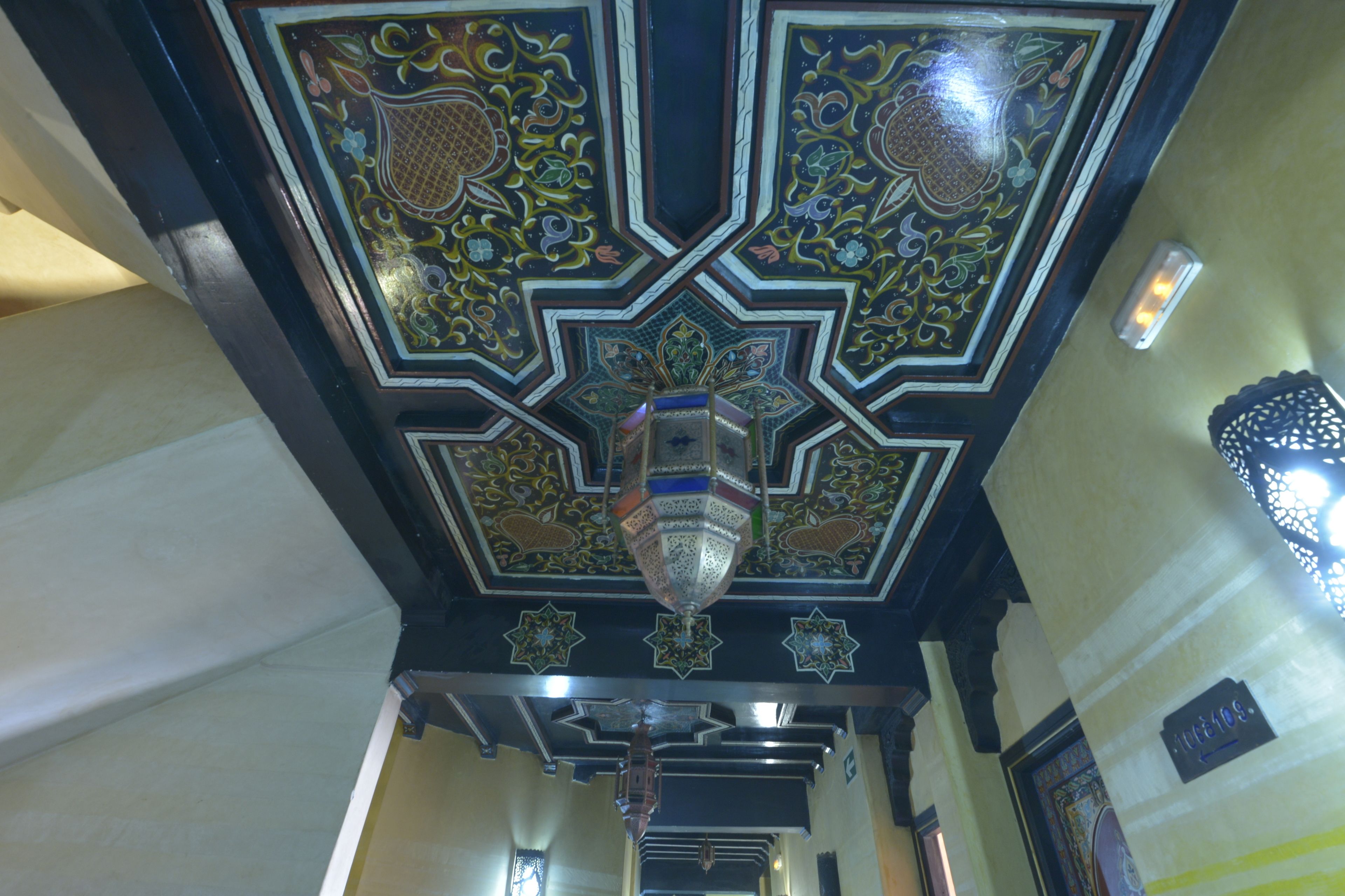 A ceiling with intricate geometric patterns and a hanging lantern.