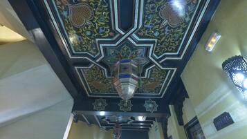 A ceiling with intricate geometric patterns and a hanging lantern.
