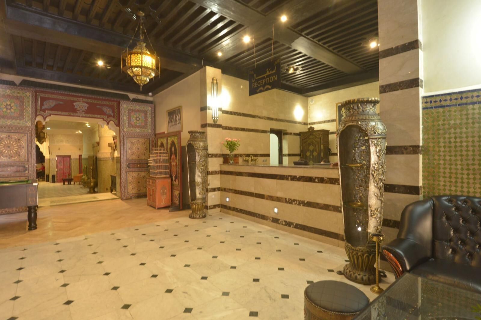 A lobby with a reception desk, ornate columns, and a patterned floor.