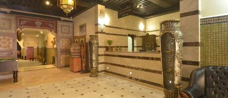 A lobby with a reception desk, ornate columns, and a patterned floor.