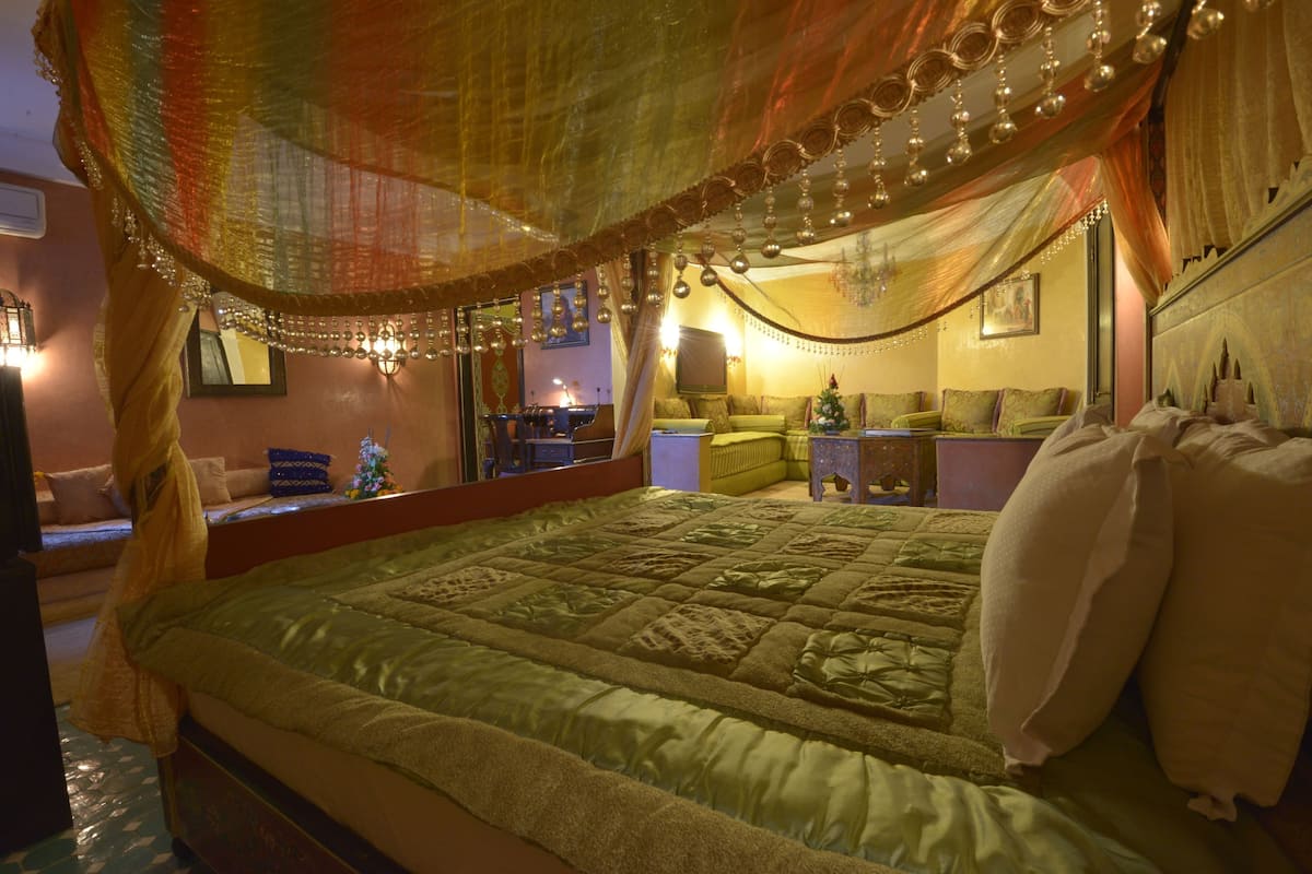 Um quarto com uma cama, mesa de cabeceira, luminária e janela.
