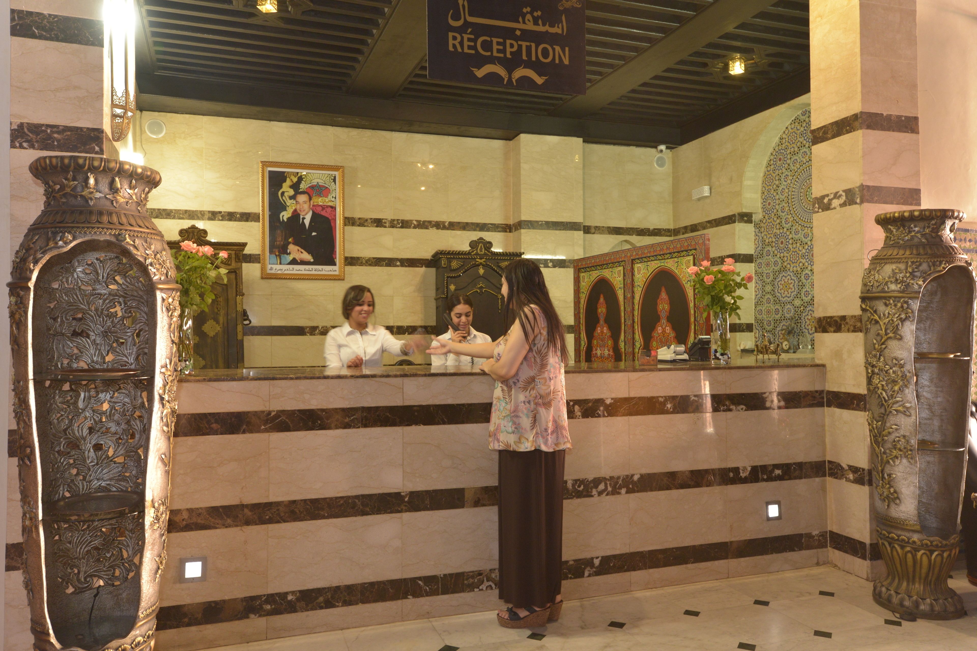 A reception area with a marble reception desk, ornate columns, and a framed portrait on the wall.