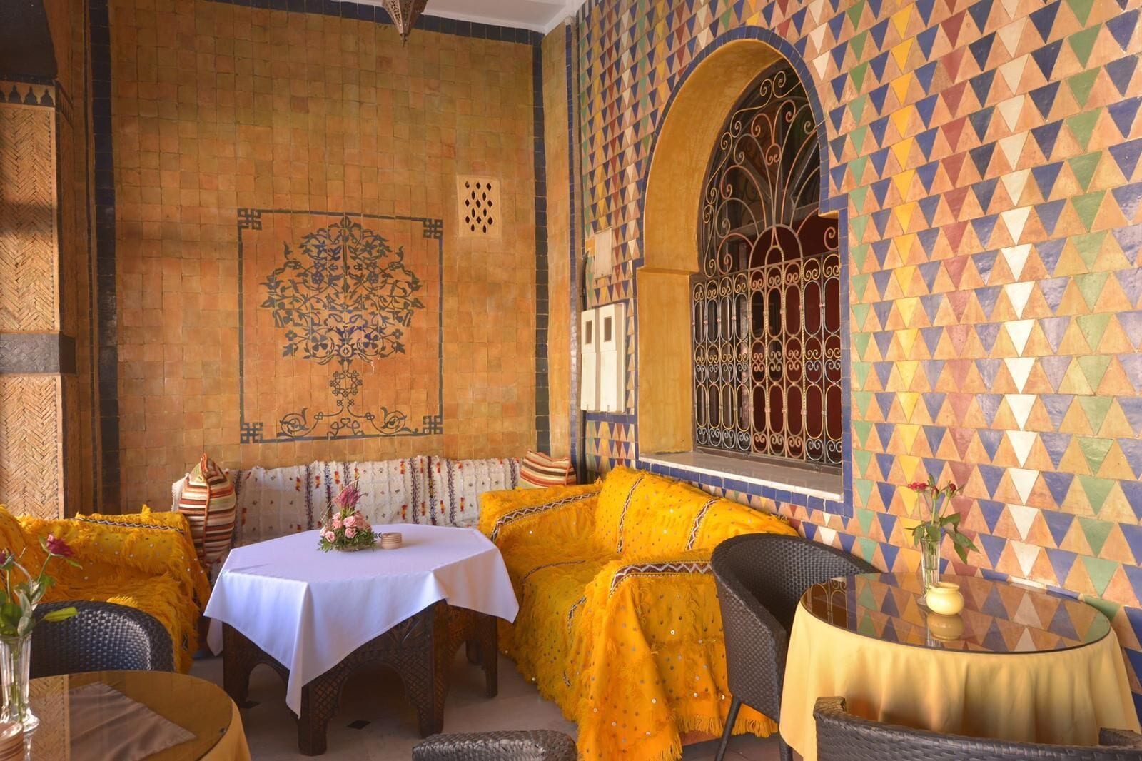 Un comedor con una mesa dispuesta para dos, un sofá y un muro con diseño.