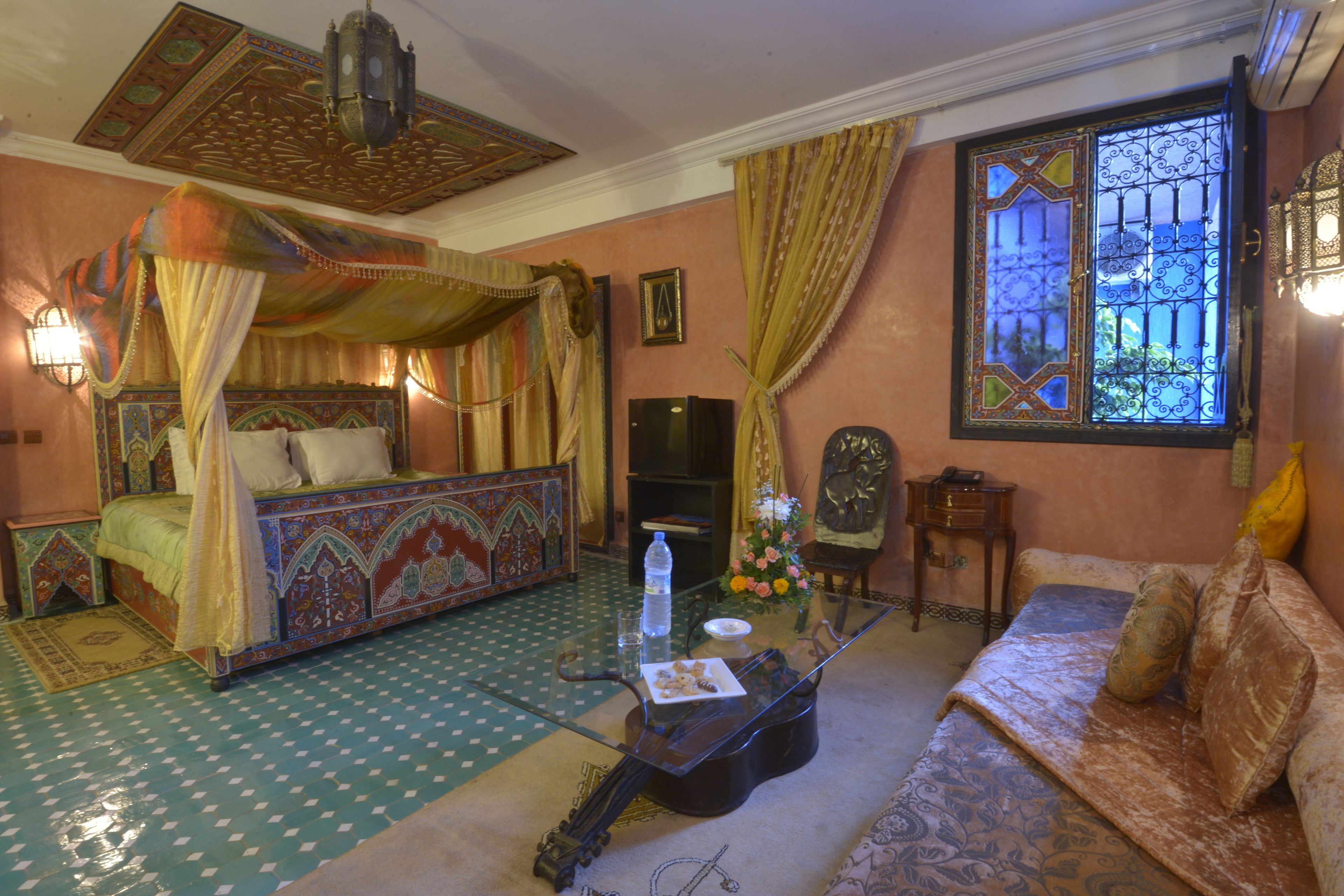 A traditional room with a four-poster bed, a sofa, and a glass coffee table.