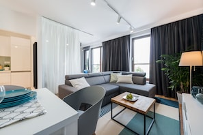 Una sala de estar moderna con sofá, mesa de comedor y zona de cocina.