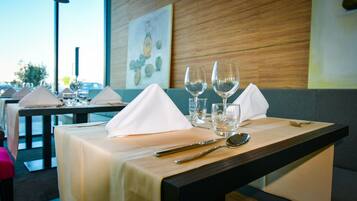 Une table de restaurant dressée avec des serviettes blanches, des verres à vin et des couverts.