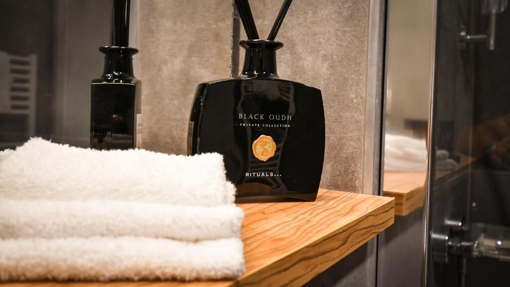 Ein Badezimmer mit einer schwarzen Flasche mit dem Aufdruck "BLACK OUDH PRIVATE COLLECTION" und einem weißen Handtuch auf einem Holzboden.