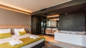 A modern hotel room with a large bed, a separate bathroom with a bathtub, and a large mirror. - Hotel Olea (Novalja)