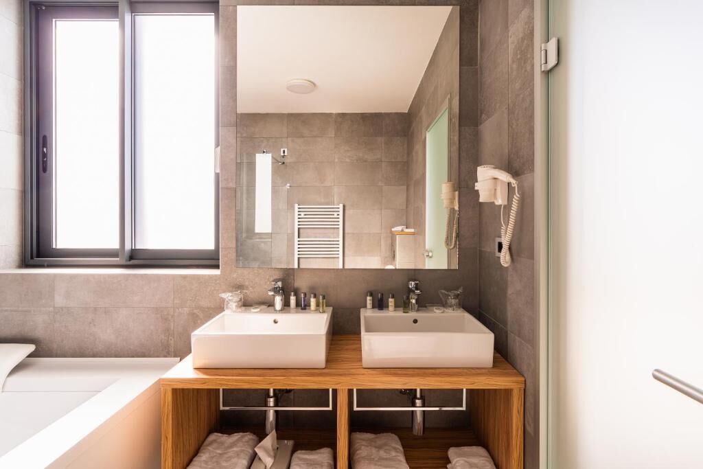 A modern bathroom with two sinks, a mirror, a towel rack, and a phone.