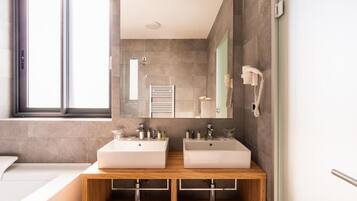 A modern bathroom with two sinks, a mirror, a towel rack, and a phone.