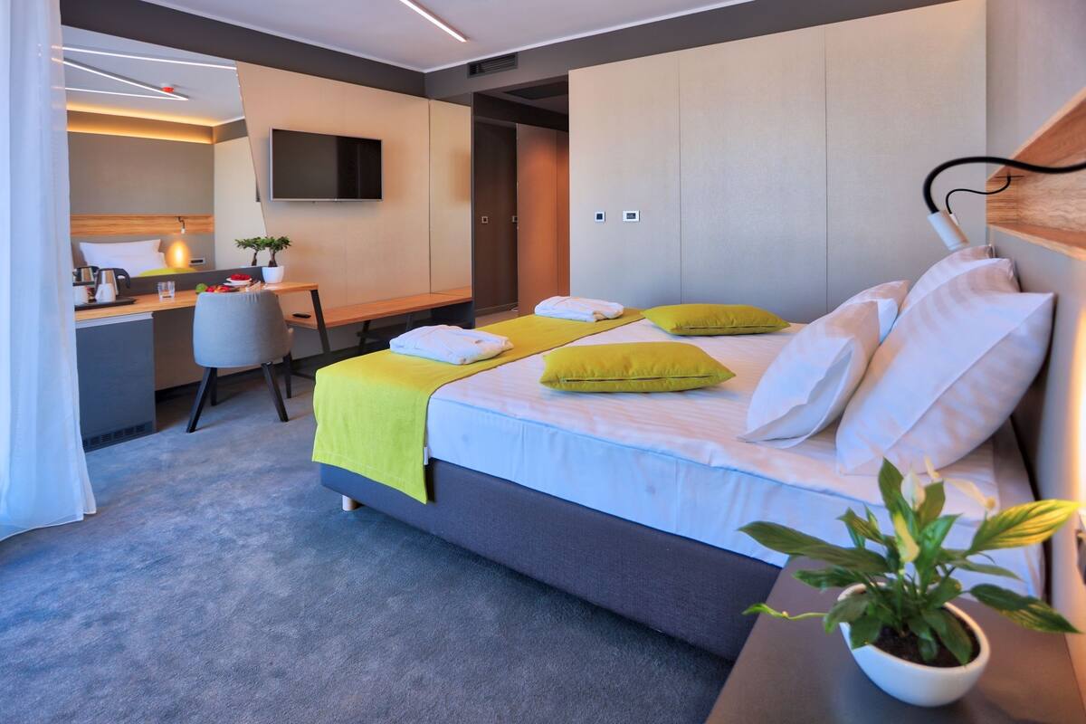 A modern hotel room with a bed, bedside table, and a desk area.