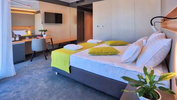 A modern hotel room with a bed, bedside table, and a desk area.