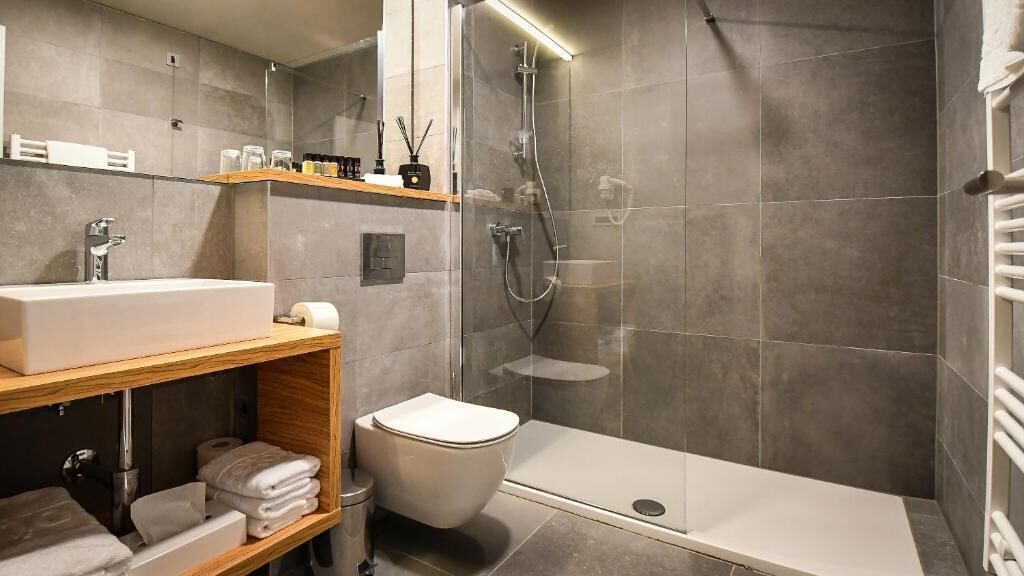 A modern bathroom with a large sink, toilet, and walk-in shower.