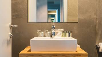 A bathroom with a white sink, mirror, and wooden vanity.