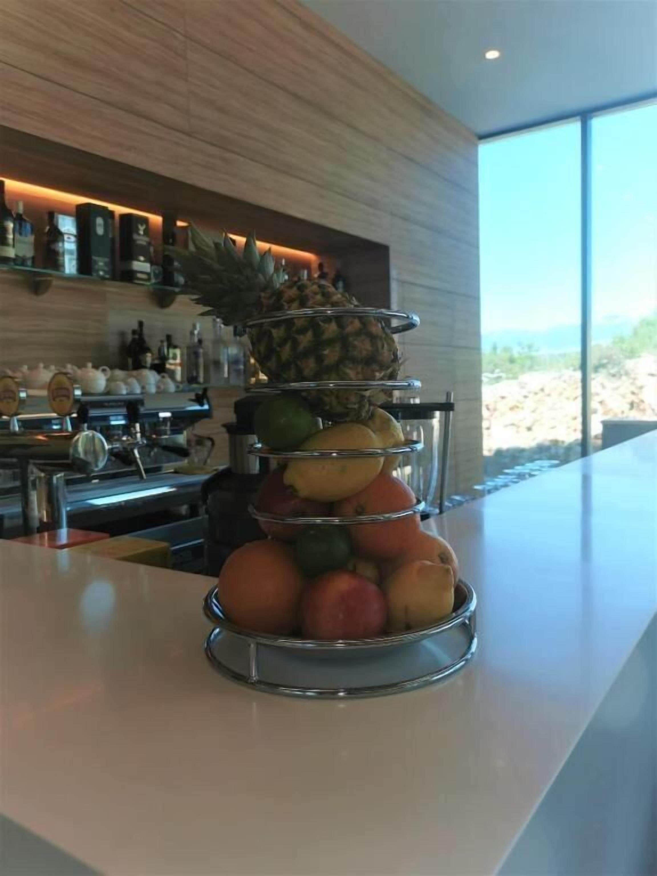 Un espositore di frutta su un bancone del bar con arredi moderni e vista sull'esterno.
