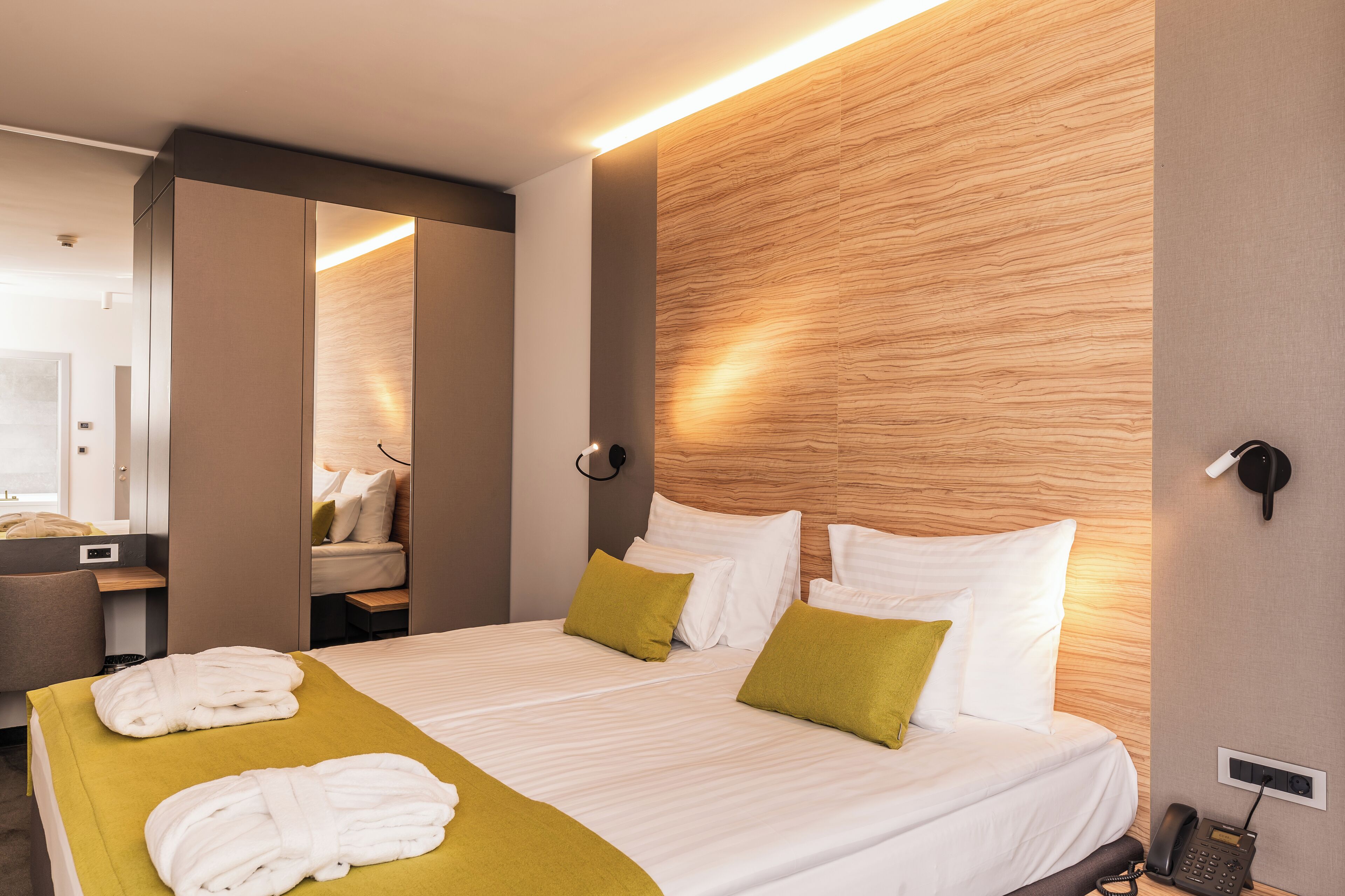 Une chambre d’hôtel avec un lit, un bureau, un miroir et un téléphone.