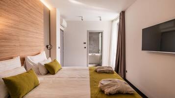 A hotel room with a large bed, a TV mounted on the wall, and a bathroom visible through an open door.