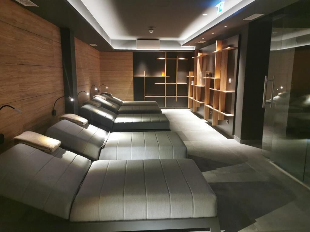 A modern spa room with massage chairs, wooden shelving, and a glass partition.
