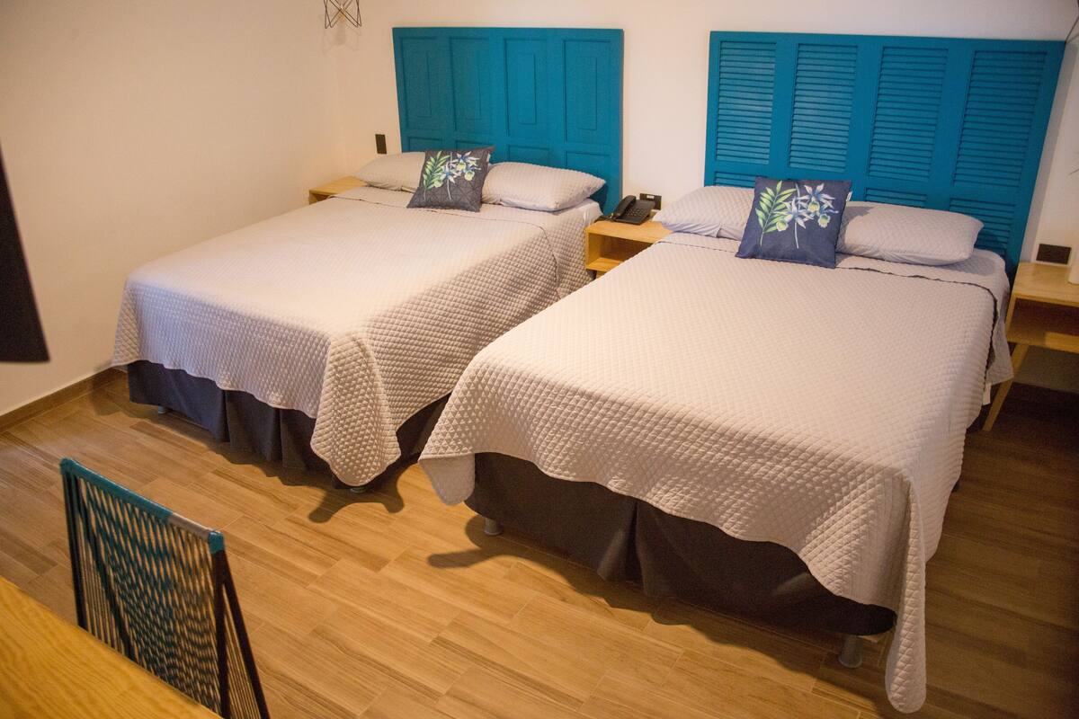 Twee eenpersoonsbedden met bijpassende hoofdborden, een houten vloer en een klein nachtkastje met een telefoon.