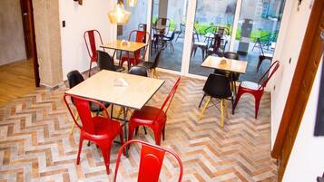 A dining area with a herringbone patterned floor, red chairs, and tables.