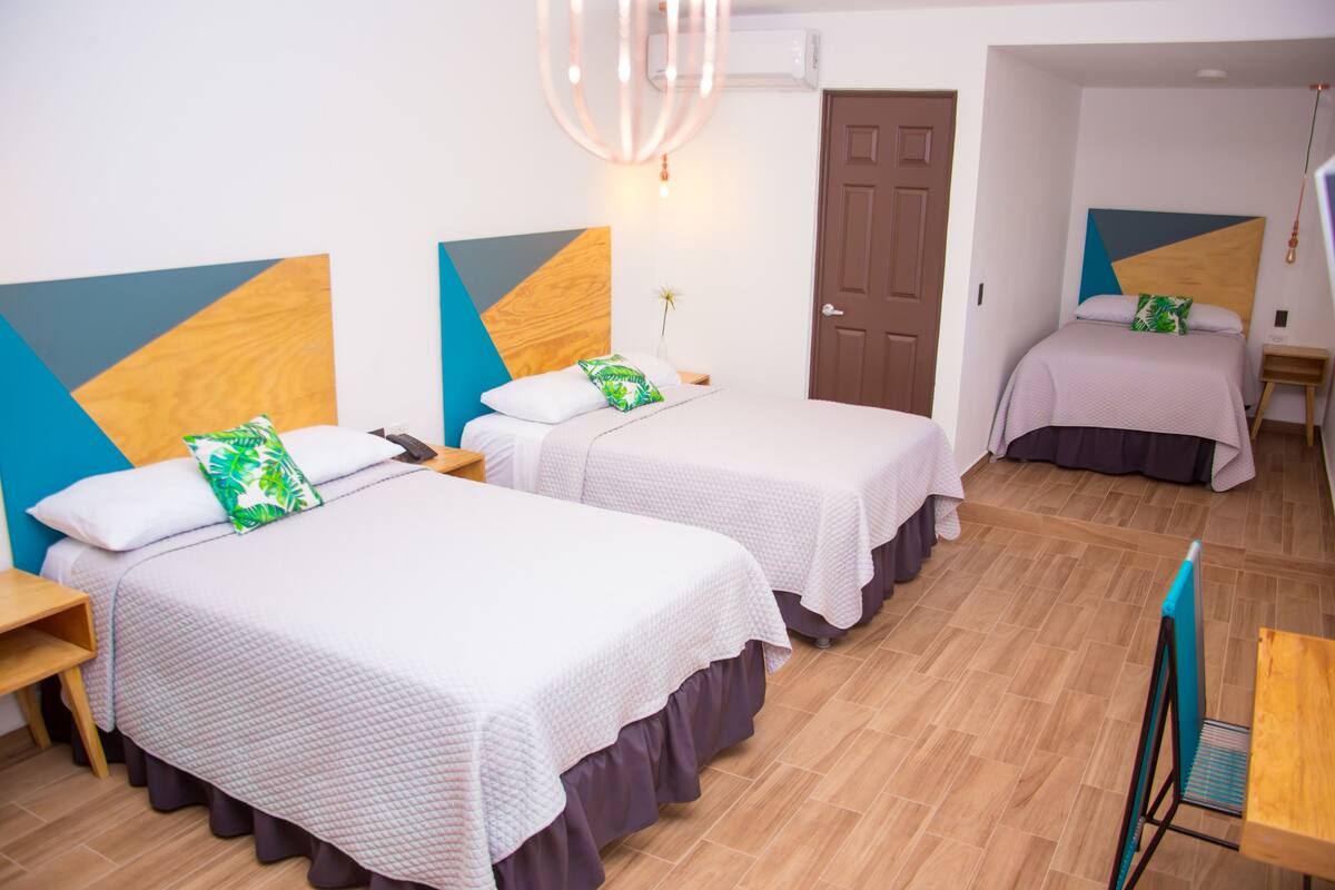Een hotelkamer met twee bedden, een houten vloer, een kroonluchter en een deur.