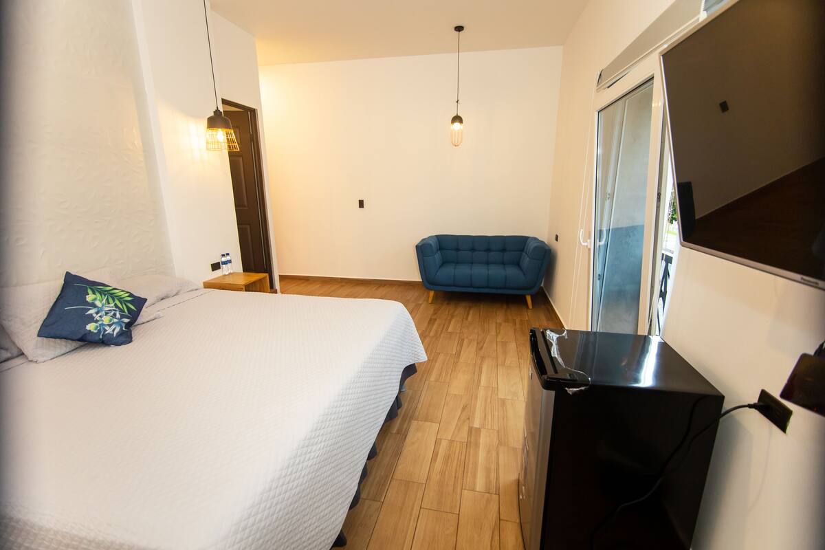 Een slaapkamer met een bed, een blauwe fauteuil, een bureau en een schuifdeur.