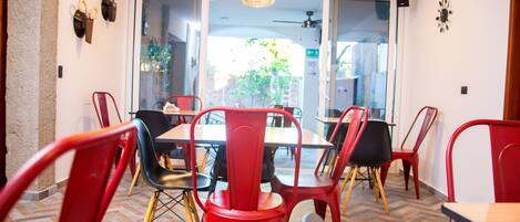 A dining area with red and black chairs, a wooden table, and a herringbone floor pattern.